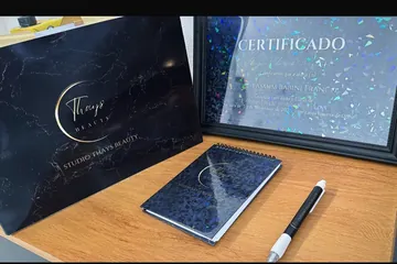 Certificado do curso sobre a mesa, ao lado de um caderno com o logotipo do studio e uma caneta.