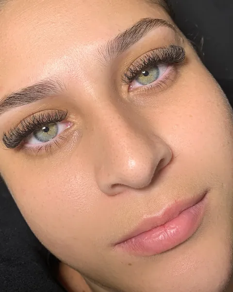 Cliente de olhos verdes com cílios volumosos e sobrancelhas definidas.