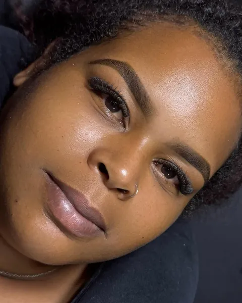 Cliente de pele negra com cílios volumosos e sobrancelhas desenhadas.