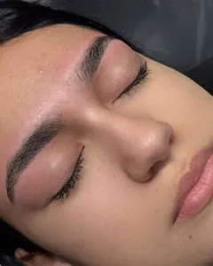 Cliente deitada, de olhos fechados, com as sobrancelhas desenhadas.