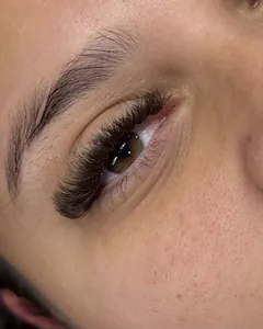 Olho de perto com extensão de cílios Mega Brasileiro em fios marrons.
