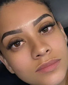 Cliente de olhos castanhos com extensão de cílios Volume Brasileiro e sobrancelhas marcadas.