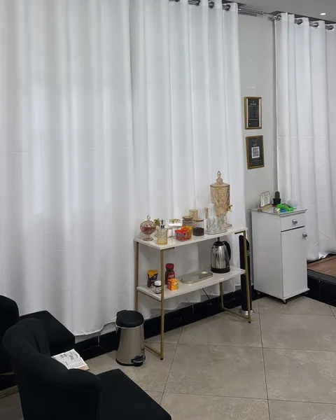 Mesa de café com chaleira, potes e suqueira de vidro âmbar, ao lado de um gaveteiro branco.